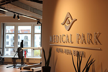 Innenraum eines Rehazentrums: An der Wand steht „Medical Park Alpha‑Reha Berlin“, daneben Trainingsgeräte, Pflanzen und große Fenster. Foto: BFV