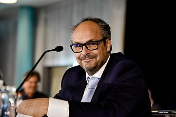 Jan Schlüschen-Hesterberg im Anzug sitzt an einem Tisch mit Mikrofon. Foto: Sandra Ritschel