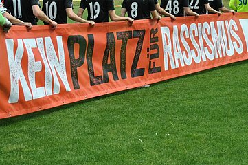 Players hold a red banner with the inscription: No place for racism, on green soccer turf. Photo: BFV