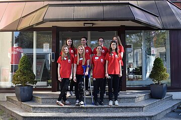 Acht Mädchen in roten T-Shirts stehen auf einer Treppe.