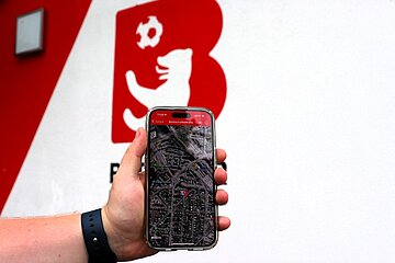 One hand holds a smartphone with a digital map on the screen. On the display is the text "Berlin Football Map". The BFV logo can be seen in the background. Photo: BFV