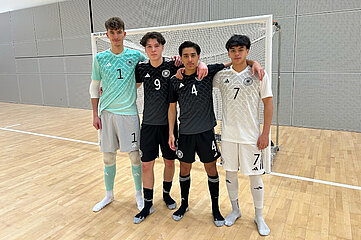 Vier Personen in Hallensportkleidung stehen eng beisammen vor einem Futsal-Tor und posieren für ein Gruppenfoto. Foto: BFV