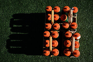 A beverage holder with many orange bottles stands on artificial turf; there is a deep shadow next to it, with warm light and clear contours visible. Photo: Eakin Howard/Getty Images