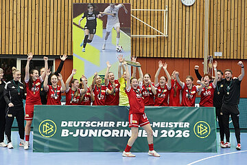 Ein Team in roten Trikots feiert in einer Sporthalle hinter einem Banner zur B‑Juniorinnen‑Meisterschaft 2026. Foto: Jens Knohr