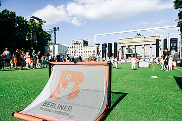 Auf einem temporären Fußballfeld mit grünem Kunstrasen vor dem Brandenburger Tor in Berlin steht im Vordergrund ein kleines Tor mit dem Logo des Berliner Fußball-Verbands. Im Hintergrund sind zahlreiche Menschen, darunter viele Kinder in bunter Sportkleidung, die sich aktiv an einem Sportevent beteiligen. Der Himmel ist blau mit vereinzelten weißen Wolken. FOTO: Sandra Ritschel
