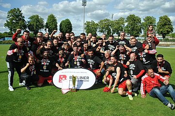 Eine Fußballmannschaft feiert auf dem Rasen den Gewinn des defendo-Pokals 2024/25 mit Pokal und Jubel. Foto: BFV