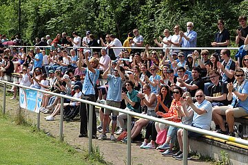 Das Bild zeigt eine größere Menschenmenge auf einer Tribüne im Freien. Einige Personen sitzen, andere stehen. Viele klatschen oder jubeln, was auf eine sportliche oder festliche Veranstaltung hinweist. Die Menschen tragen überwiegend legere Kleidung. Foto: BFV