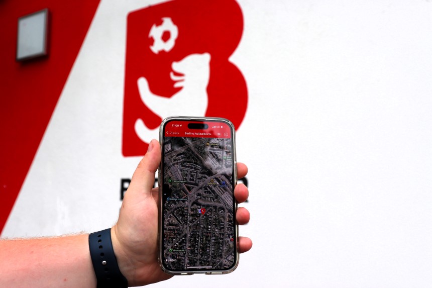 Eine Hand hält ein Smartphone, auf dessen Bildschirm eine digitale Karte zu sehen ist. Auf dem Display steht der Text „Berlin Fußballkarte“. Im Hintergrund ist das Logo des BFV zu erkennen. Foto: BFV