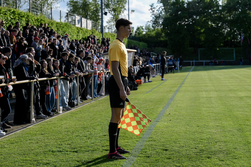 Person with linesman's flag on the edge of the pitch; full stands, green pitch, sunny outdoor game with clear lines. Photo: Sandra Ritschel