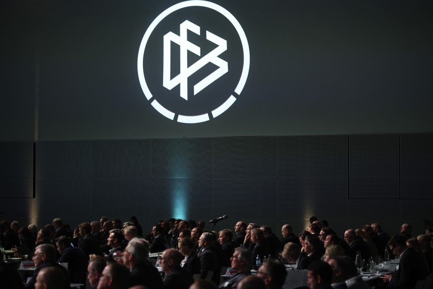 Large hall with many seated people, the DFB logo is emblazoned on the wall in white projection. Photo: Alex Grimm/Getty Images
