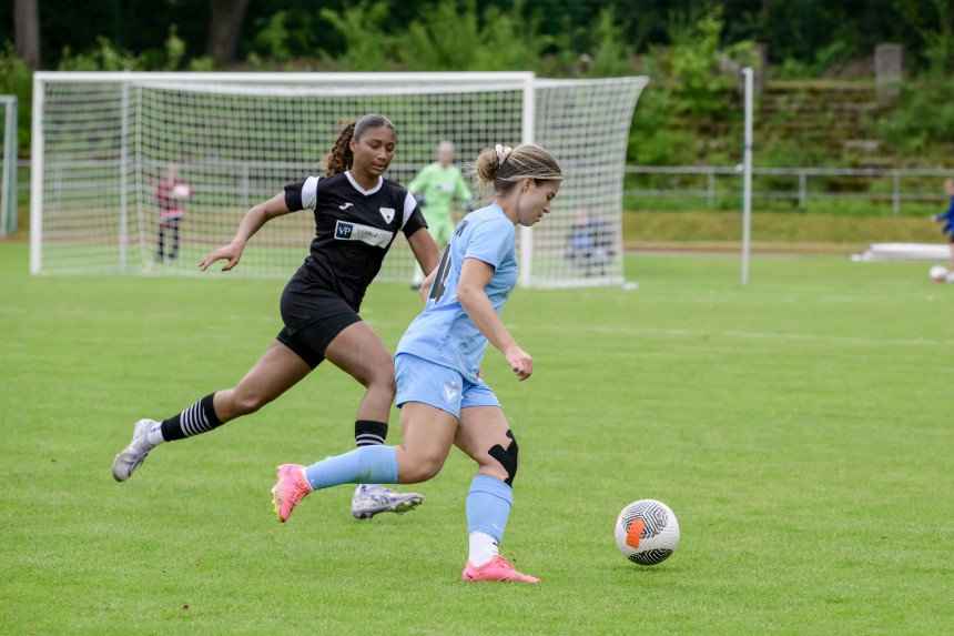 Spielerin in Hellblau dribbelt den Ball, verfolgt von Spielerin in Schwarz. Im Hintergrund steht ein Fußballtor. Foto: Sandra Ritschel