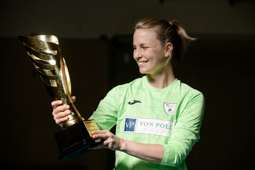 Eine Fußballspielerin im grünen Trikot hält einen goldenen Pokal in den Händen. Foto: Sandra Ritschel