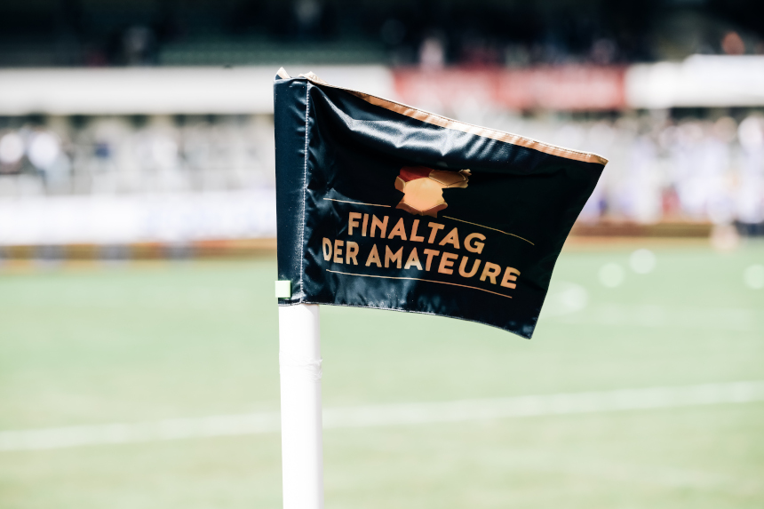 Eine Eckfahne mit der Aufschrift „Finaltag der Amateure“ steht am Spielfeldrand, das Stadion ist unscharf im Hintergrund zu sehen. Foto: Sandra Ritschel