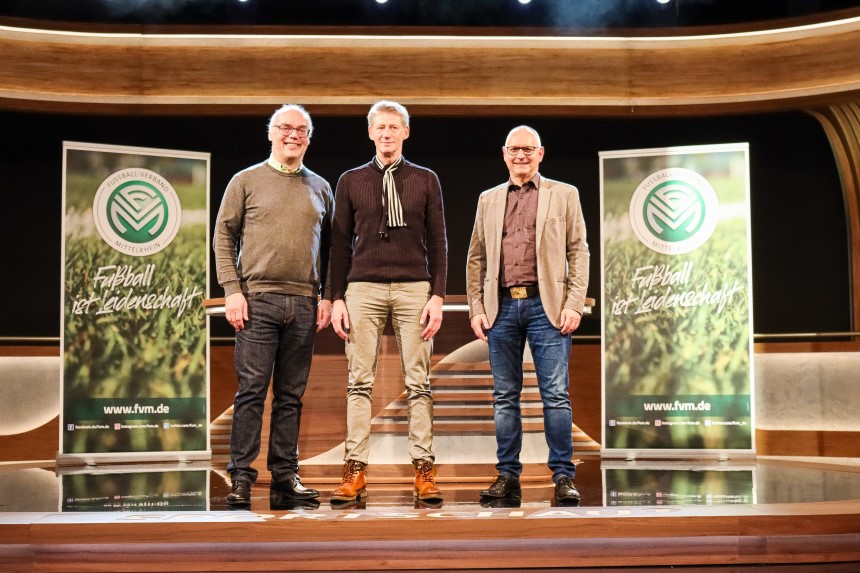 Drei Männer stehen auf einer Bühne zwischen zwei Bannern des Fußballverbands Mittelrhein. Foto: FVM