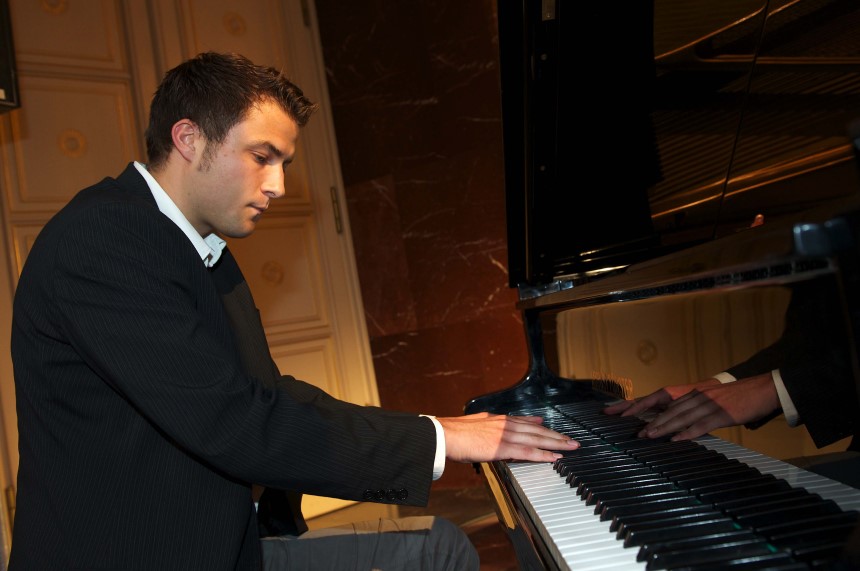 Ein Mann im Anzug spielt Klavier in einem eleganten Raum. Foto: TOP Sportmarketing