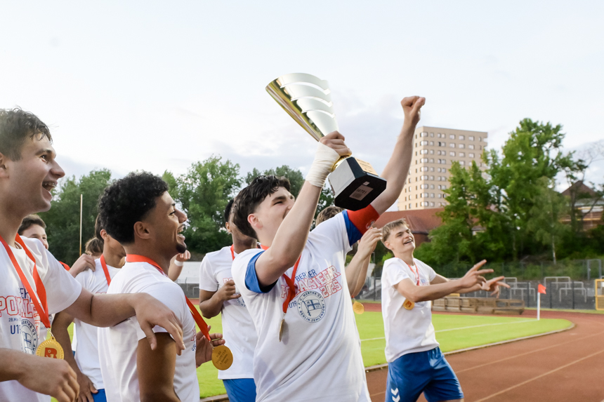 Mehrere Personen in Sportkleidung halten gemeinsam einen Pokal hoch, tragen Medaillen und stehen auf einer Laufbahn im Stadion. Foto: Sandra Ritschel