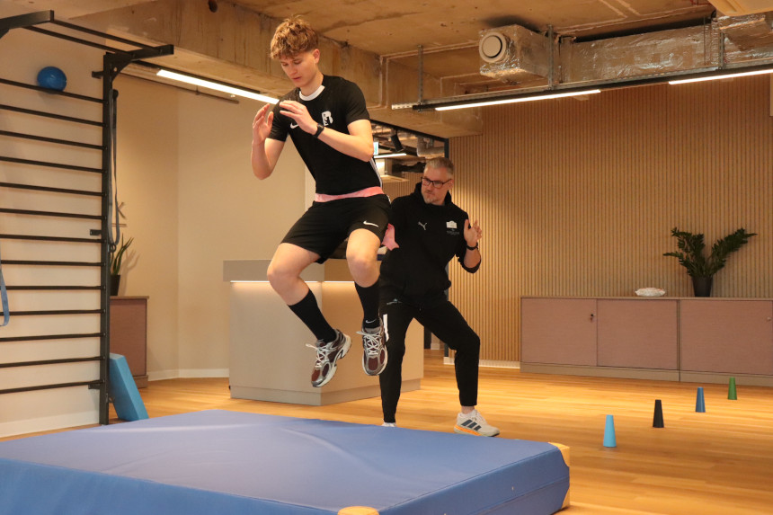 In einem Trainingsraum springt eine Person von einer Matte, begleitet von einer Fachkraft; im Raum stehen weitere Trainingsgeräte bereit. Foto: BFV