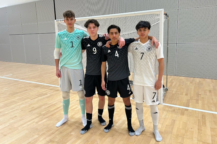 Vier Personen in Hallensportkleidung stehen eng beisammen vor einem Futsal-Tor und posieren für ein Gruppenfoto. Foto: BFV