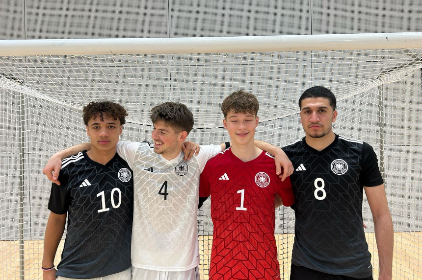 Vier Personen in Sportkleidung stehen eng vor einem Hallentor und legen einander die Arme um die Schultern für ein Gruppenfoto. Foto: BFV