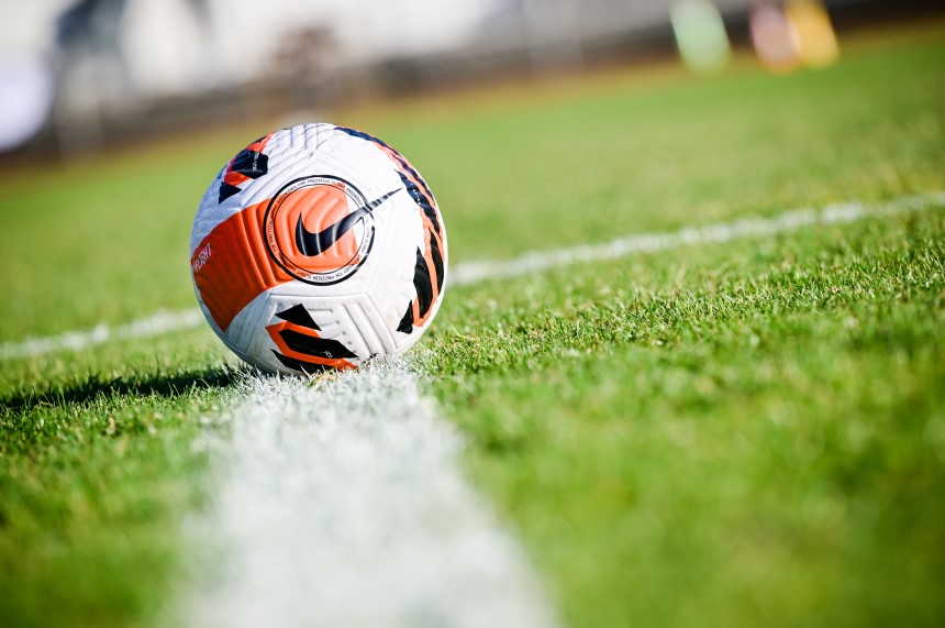 Ein Fußball liegt auf einer grünen Rasenfläche direkt an einer weißen Spielfeldlinie, im Hintergrund unscharfe Farben. Foto: Sandra Ritschel