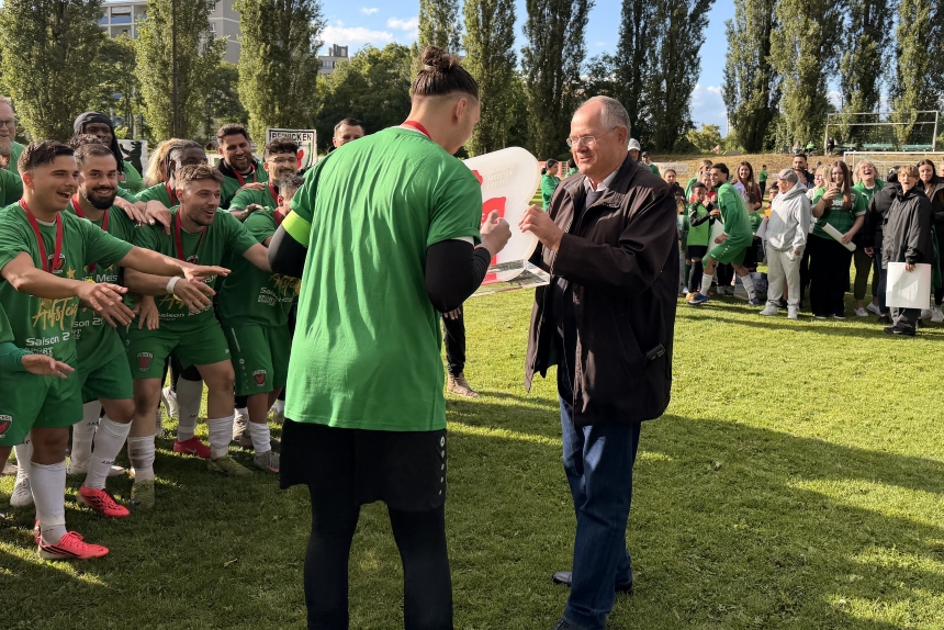 A team in green jerseys at a championship celebration on the soccer field; the presentation of a trophy in front of the team and the crowd.
